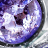 Серебристая гладкая коническая анальная пробка с фиолетовым кристаллом - 7 см. купить в секс шопе